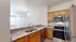 Modern kitchen with sleek granite countertops, stainless steel appliances, and warm wooden cabinetry, illuminated by elegant pendant lighting.
