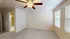 Bright and cozy bedroom with soft carpet flooring, ceiling fan, and ample natural light from large windows, adjacent to a modern ensuite bathroom.