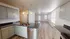 Bright open-concept kitchen with sleek dark countertops and modern cabinetry, leading to a spacious living area with elegant wood flooring.