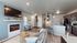 Modern open-concept living space featuring a cozy fireplace, sleek kitchen with granite countertops, and stylish furnishings.