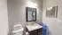 Modern bathroom with elegant granite countertop, stylish framed mirror, and contemporary wall art, exuding a serene and sophisticated ambiance.