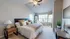 Inviting bedroom with plush bedding, modern decor, and ample natural light, showcasing a cozy and stylish atmosphere.