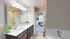Modern bathroom with dual sinks, elegant lighting, and a view into a cozy bedroom with plush carpet and abundant natural light.