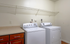In-unit laundry room with washer and dryer, countertop, cabinet storage, and overhead wire shelving.