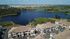 Breathtaking aerial view of a modern lakeside apartment complex surrounded by lush greenery and expansive scenic water views.