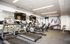 Modern fitness center with cardio machines, weights, and wall-mounted TVs.