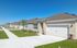 Charming suburban neighborhood with modern beige homes, neat lawns, and tranquil blue skies.