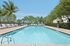 Inviting outdoor pool surrounded by lush palm trees and comfortable lounge chairs, perfect for relaxation and enjoyment.