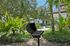 Outdoor patio featuring a barbecue grill surrounded by lush greenery and a cozy seating area.