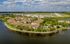 Aerial view of elegant lakeside apartments with charming terracotta roofs surrounded by lush greenery and scenic water views, enhancing a serene lifestyle.