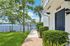 Charming waterfront apartment entrance with lush greenery, palm trees, and serene lake views.