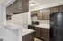 Modern kitchen with sleek brown cabinetry, elegant countertops, and black appliances.