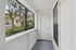 Inviting enclosed porch with large windows showcasing a serene view of lush trees, perfect for relaxing and enjoying nature.