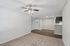 Inviting living space featuring plush carpet, sleek hardwood floor transition, and modern ceiling fan in an open layout apartment.