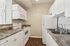 Modern apartment kitchen featuring sleek white cabinetry, stylish countertops, and stainless steel appliances, including a microwave and electric stove.