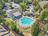 Aerial view of a luxurious residential complex featuring a sparkling swimming pool, lush greenery, and stylish modern buildings, perfect for relaxation and leisure.