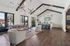 Elegant open-concept clubhouse with vaulted ceilings, featuring modern lighting, cozy seating, and a chic kitchen with bar stools and stylish decor.
