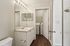Elegant bathroom featuring a wide mirror, sleek vanity, and convenient in-unit laundry area with washer and dryer.