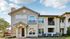Charming two-story apartment building with elegant balconies and stone accents, set against a bright blue sky.