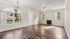 Inviting living room with elegant chandelier, large sunlit windows, and cozy fireplace, featuring sleek hardwood flooring.