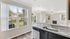 Bright and inviting living area with stylish granite countertops, modern chandelier, and large windows overlooking a serene neighborhood view.