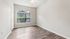 Bright and inviting bedroom featuring elegant hardwood floors, large arched window, and soothing neutral walls.