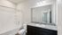 Elegant bathroom with granite countertop, large mirror, and modern lighting fixtures, offering a serene retreat.