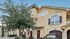 Charming townhouse exterior with a Mediterranean design, featuring stucco walls, arched windows, and a welcoming driveway.