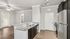 Sleek modern kitchen with granite countertops, stainless steel appliances, and elegant wood flooring in a bright, open-concept space.