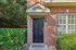 Inviting brick exterior with a stylish black door, framed by lush greenery for a warm welcome.