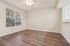 Bright living area with modern wood flooring, large window with garden view, and overhead ceiling fan.