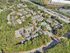 Aerial view of a vibrant apartment complex featuring lush greenery, spacious parking areas, and a refreshing central swimming pool, offering a serene residential oasis.