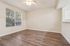 Bright and inviting living space with large window, elegant ceiling fan, and stylish wood flooring.