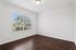 Bright, unfurnished room with elegant dark hardwood floors and large window with scenic outdoor view.