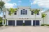 Charming Mediterranean architecture, featuring a tiled roof and vibrant palm trees, offering spacious two-car garages.