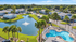 Aerial view of Willow Lake Crossing with gray and white apartment buildings, a pond fountain, palm trees and swimming pool.