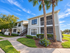 Gray and white apartment building at Willow Lake Crossing with landscaped grounds.