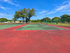 Red and green tennis courts at Willow Lake Crossing with perimeter fencing and palm trees.