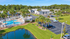 Aerial view of Willow Lake Crossing with updated gray and white buildings, a swimming pool, palms and pond.