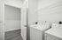 side by side white washer dryer on gray planking with white walls in laundry room