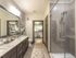 Model bathroom at our 55 and over apartments in Flower Mound, featuring tiled floor paneling and a view of the bedroom.