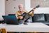 55+ man playing the guitar in his home