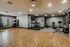 Modern apartment gym with state-of-the-art treadmills, exercise bikes, free weights, and a spacious wooden floor for workout classes.