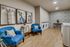 Stylish laundry room featuring modern washers, intricate tile wall, and cozy seating with vibrant blue chairs and artistic decor.