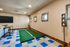 Chic recreational room featuring indoor putting green, stylish two-tone tiled floor, and cozy seating area.