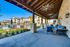 Inviting outdoor patio with cozy blue seating under wooden beams, offering views of a sparkling pool and modern apartment buildings.