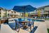 Luxurious apartment complex with a stunning outdoor pool area featuring stylish loungers and vibrant blue umbrellas, perfect for relaxation and social gatherings.