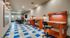 Modern and inviting co-working space with vibrant blue and white checkered flooring, featuring sleek orange workstations and comfortable seating, perfect for productivity and collaboration.