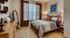 Inviting bedroom with cozy bedding, elegant decor, and warm natural lighting from large window curtains.