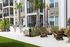 Modern apartment exterior featuring lush landscaping, inviting outdoor seating, and built-in stainless steel grills, perfect for entertaining.